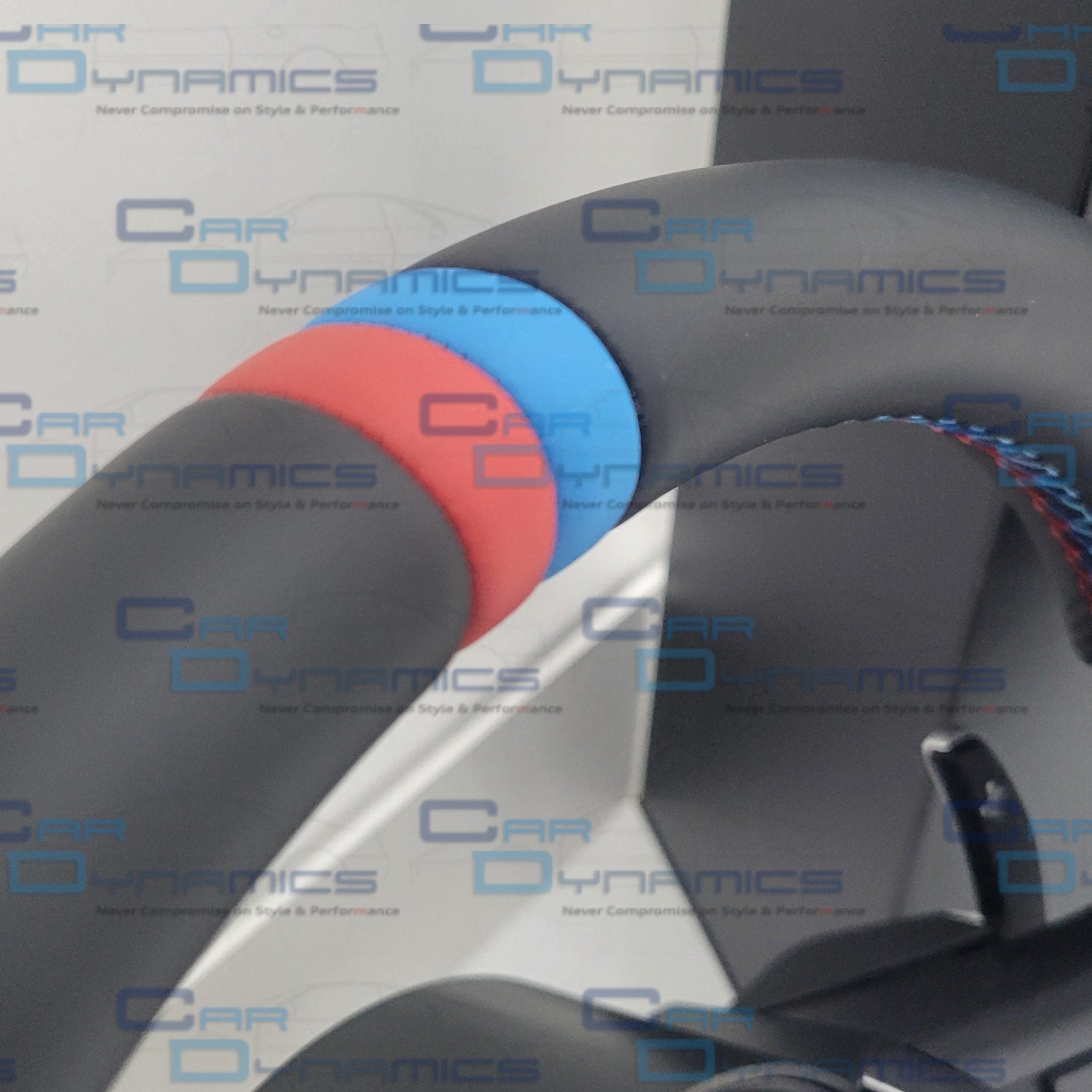 Close-up of a car bmw steering wheel with red, blue, and black accents on a white background with 'Car Dynamics' branding.