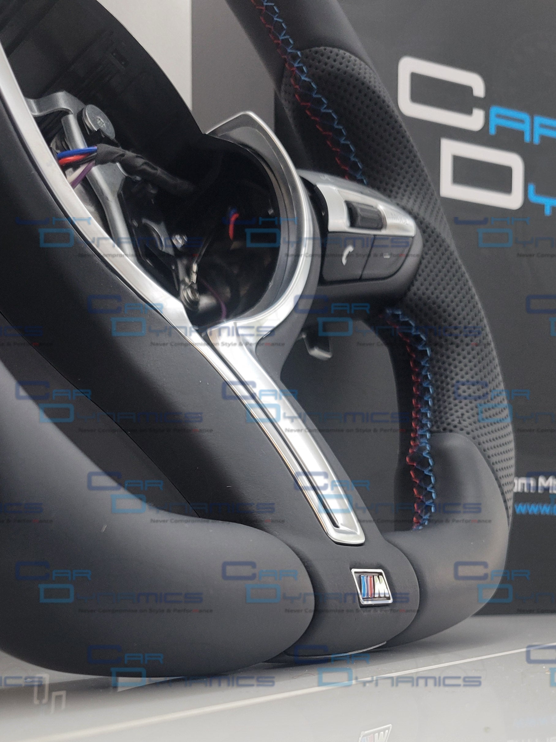 Close-up of a car steering wheel with visible branding on a white surface.