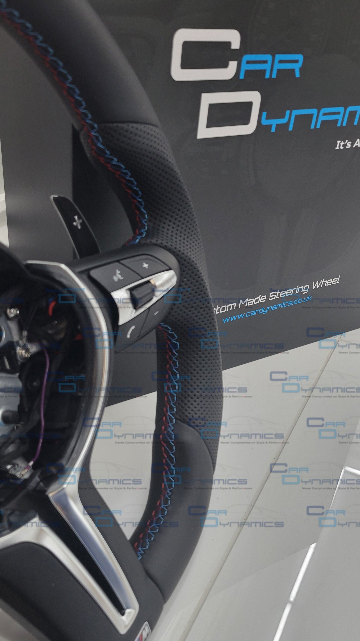 Close-up of a car bmw steering wheel with visible branding on a reflective surface.